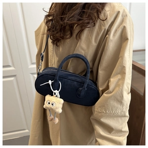 Model wearing a black matte pillow bag with long handles and a cute plush charm