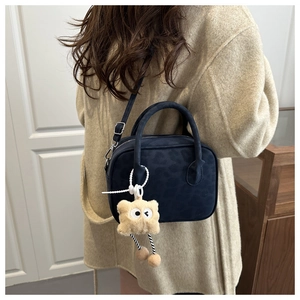 Détail du sac bandoulière bleu foncé à motif léopard avec pendentif en peluche