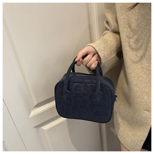 Détail de la texture léopard sur sac à main en velours avec fermeture éclair argentée