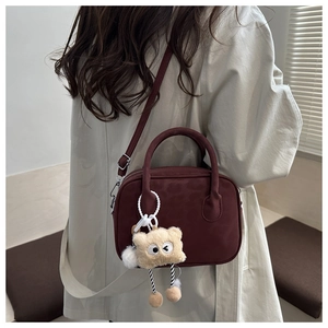 Model wearing a vintage burgundy shoulder bag with a cute plush bear charm detail