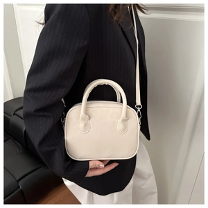 Sac à main minimaliste crème avec doubles poignées et bandoulière amovible porté sur modèle
