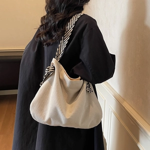 Off-white corduroy hobo shoulder bag with striped strap shown on a female model