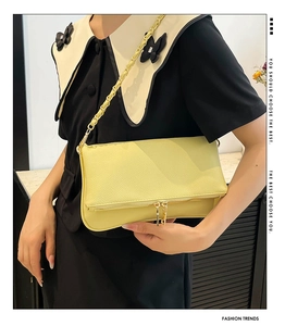 Detail of light yellow lychee grain leather shoulder bag with gold chain strap detail