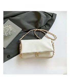 Detail view of white lychee leather texture and golden metal chain on shoulder bag