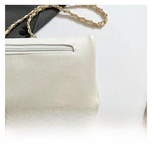 Detail of white pebbled leather crossbody bag with back zipper and chain strap