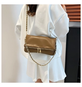Detailed view of brown leather crossbody bag with gold chain strap on model