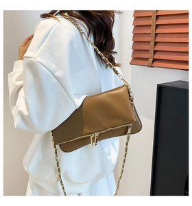 Detail of a brown faux leather shoulder bag with golden chain strap and decorative zippers