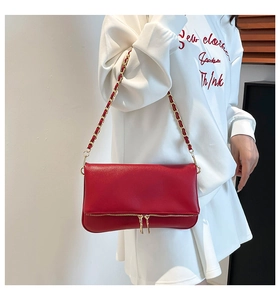 Detail of red pebbled leather underarm bag with gold double zippers and chain strap