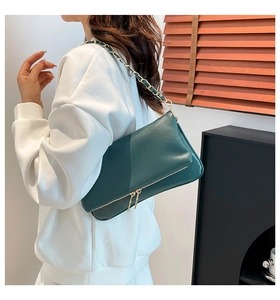 Detail of dark green pebble leather bag with gold chain strap and dual zippers