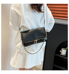 Close-up of black lychee grain leather crossbody bag with gold chain strap and dual zippers