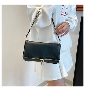 Detail view of black lychee leather crossbody bag with decorative zippers and chain strap