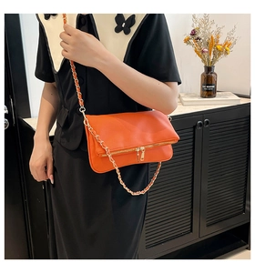 Detail of orange litchi grain leather bag with gold metal zipper and chain strap