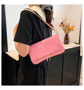 Detailed texture of pink litchi grain leather bag with golden chain and zipper