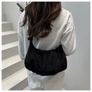 Rear view of a model wearing a black suede crossbody bag on minimalist white stairs