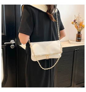 Detail of white leather crossbody bag with gold chain strap and dual zipper closure