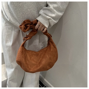 Close-up of brown suede crescent bag with stylish ruched handle detail for winter