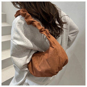 Détail du sac hobo en daim caramel avec bandoulière plissée porté par un mannequin