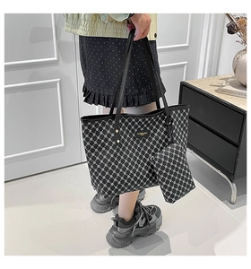 Detail of black tote bag and matching pouch with white geometric patterns and leather straps