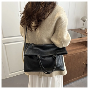 Grande borsa tote in pelle martellata nera indossata da modella in ambiente interno