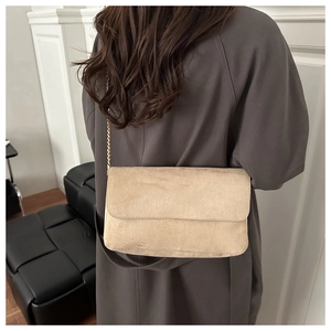 Detailed view of beige faux suede crossbody bag featuring elegant gold chain strap