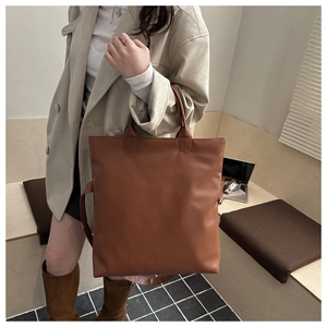 Borsa tote in ecopelle marrone con trama litchi indossata da modella con trench beige