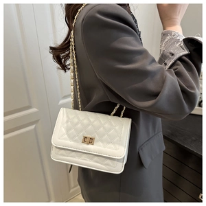 Sac à bandoulière matelassé blanc avec chaîne dorée porté par un mannequin en intérieur