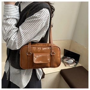 Detailed view of the brown leather shoulder bag with decorative silver metal rings