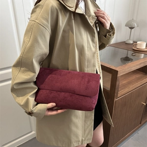 Chic burgundy suede shoulder bag with gold chain strap on khaki trench coat