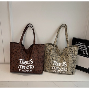 Detail of leopard print tote bags with bold white text on textured canvas surface