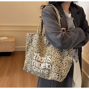 Close-up of leopard print canvas tote bag with graphic text worn by a model