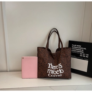 Detail shot of leopard print canvas tote bag with 'There is more to Come' white script text
