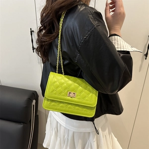 Petit sac carré matelassé vert citron avec chaîne dorée porté sur veste en cuir