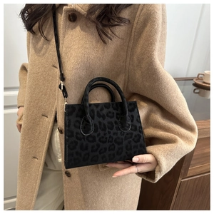 Detail of leopard print faux fur handbag styled with a camel coat and shoulder strap