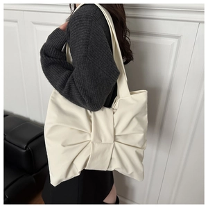 Detailed side view of white tote bag with oversized bow design on leather material