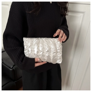 Detail der perlweißen Plisse-Clutch mit Metallic-Glanz und gesteppter Textur für Damen