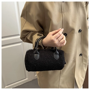 Detail of black faux fur cylinder bag featuring leather handles and metal zipper top