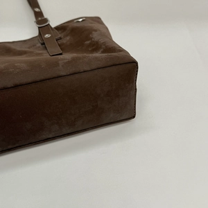 Dettaglio ravvicinato della base ampia e fibbie argentate della borsa tote marrone