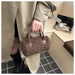 Detail of plush brown teddy fleece barrel bag with smooth leather handles and zip closure