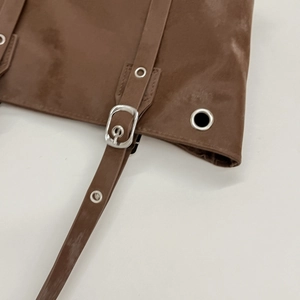 Dettaglio della borsa tote in pelle marrone con finitura martellata e fibbia in metallo argento