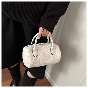 Detailed close-up of a white plush teddy faux fur boston bag with leather handles