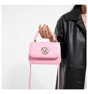 Bolso rosa acolchado con logo M dorado sostenido por modelo con chaqueta de cuero negro