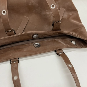 Dettaglio borsa tote in pelle marrone scuro con chiusura magnetica e occhielli in metallo