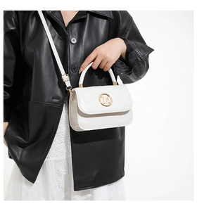 Detalle de mini bolso blanco acolchado con logo M dorado y correa ajustable de moda