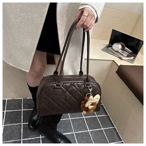 Detail of dark brown quilted shoulder bag with cute plush bunny ear charm accessory