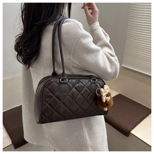 Detail of dark brown quilted bowling bag with plush bear charm and silver zipper