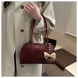 Detail of burgundy quilted faux leather bowling bag with cute plush doll pendant accessory