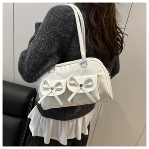 Detail of white glossy bowling bag with decorative twin bows and front flap pockets