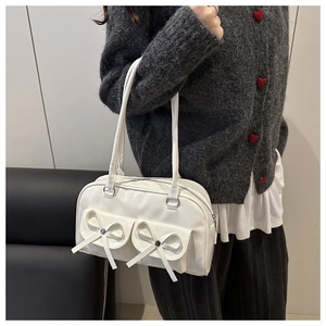 Detail of white glossy bowling bag with decorative pockets and ribbon on shoulder