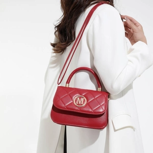 Sac à main en cuir matelassé rouge avec logo M doré porté avec un costume blanc élégant