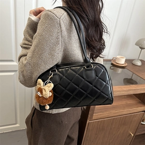 Quilted black rhombus shoulder bag with plush charm shown in a cozy home setting